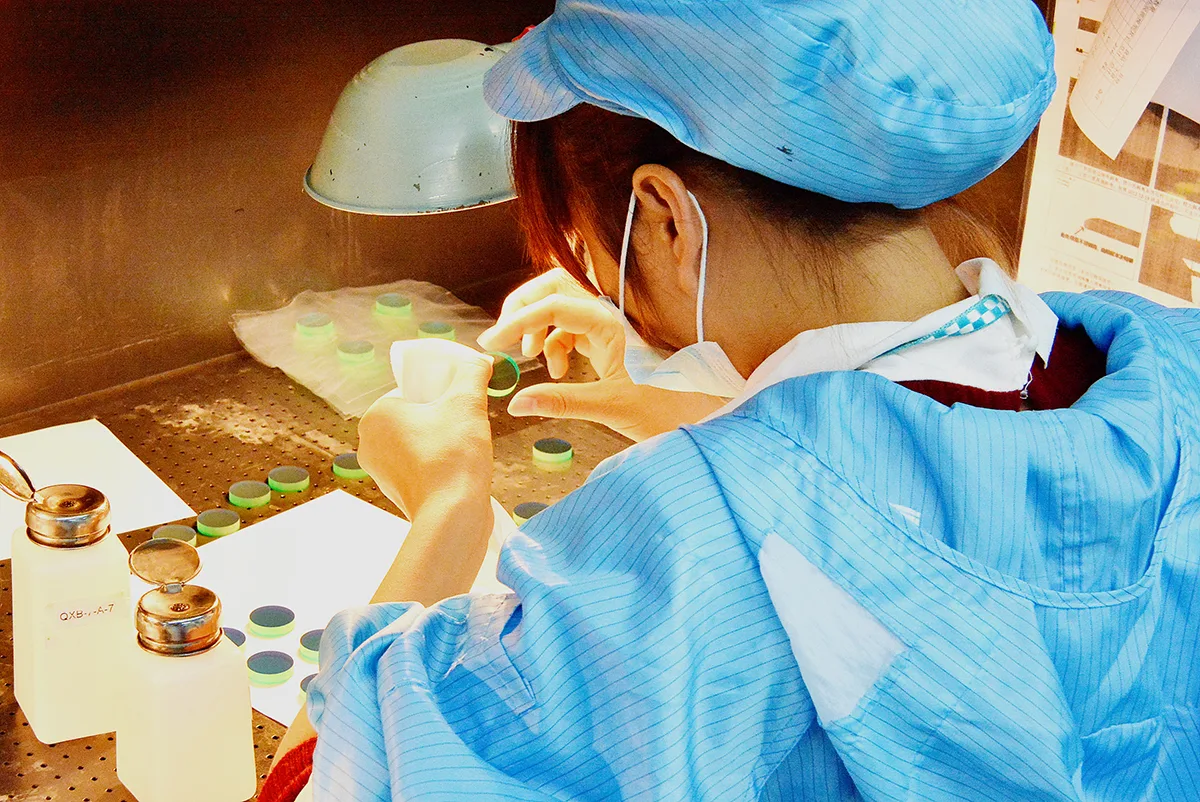 GIAI technician inspecting optical components during production